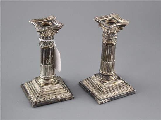 A pair of Edwardian silver corinthian column dwarf candlesticks by Williams Ltd, Birmingham, 1905, height 16.4cm, weighted, a.f.